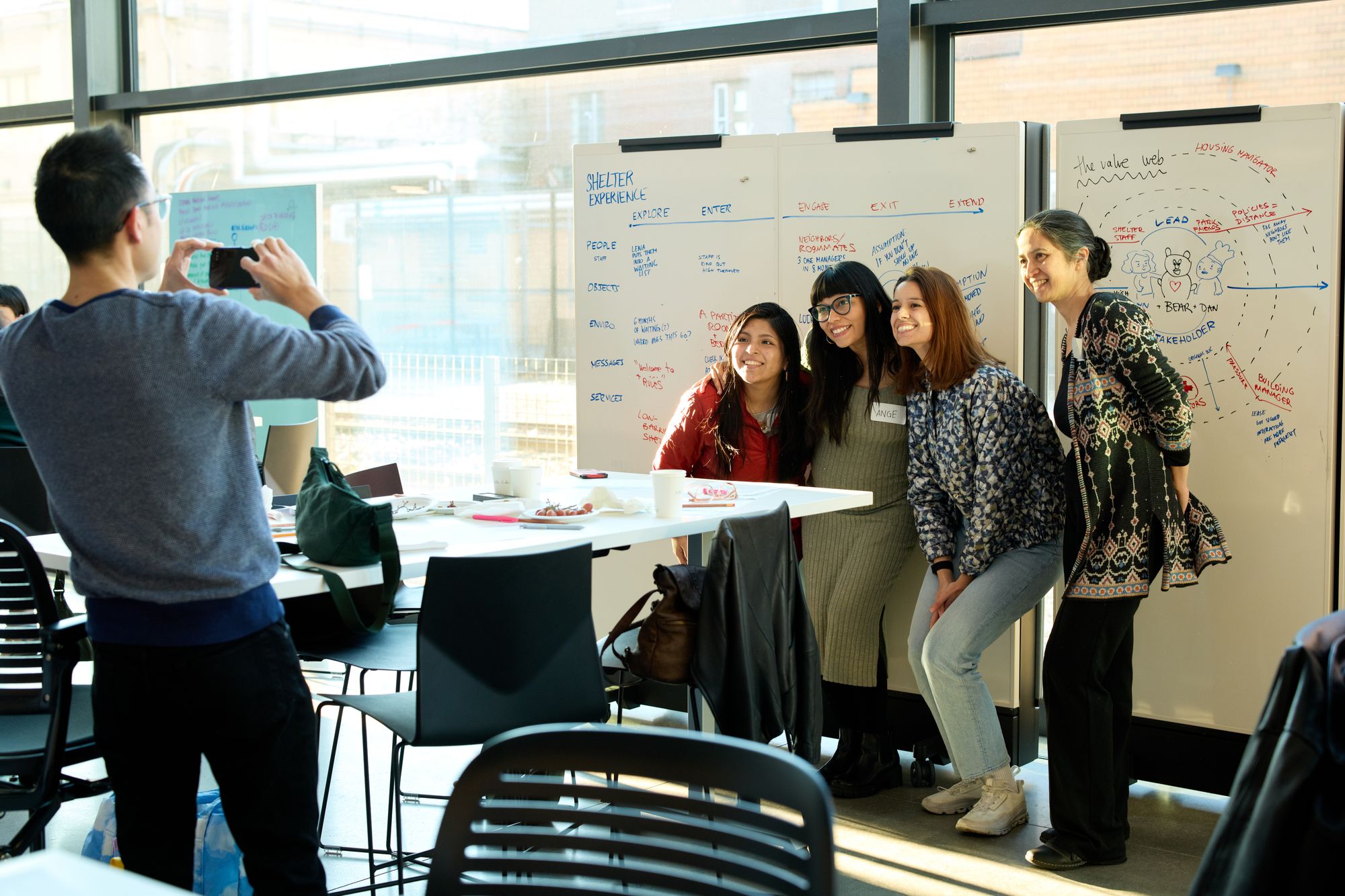 One group poses for a photo below their whiteboard.